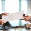 Business person giving partnership agreement to coworker